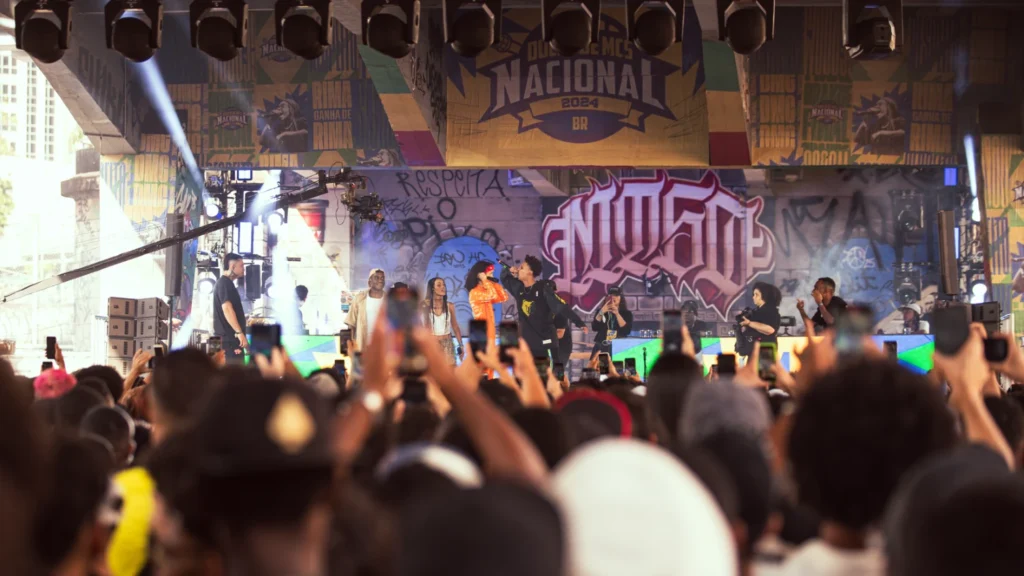 MCs batalhando no palco do Duelo de MCs Nacional 2025 em BH, com a plateia animada.